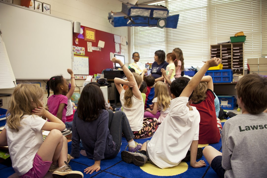 Crafting Captivating Headlines: Your awesome post title goes here Captured in a metropolitan Atlanta, Georgia primary school, this photograph depicts a typical classroom scene, where an audience of school children were seated on the floor before a teacher at the front of the room, who was reading an illustrated storybook, during one of the scheduled classroom sessions. Assisting the instructor were two female students to her left, and a male student on her right, who was holding up the book, while the seated classmates were raising their hands to answer questions related to the story just read.